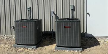Two outdoor air conditioning units beside a building.
