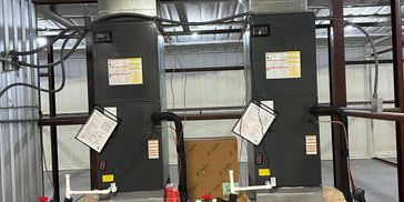 Two large industrial machines with warning labels in a warehouse.