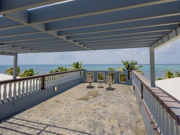 Covered rooftop terrace with ocean view and two chairs.