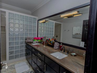 Modern bathroom with dual sinks and glass block shower partition.
