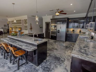 Modern kitchen with marbled countertops and black cabinetry.