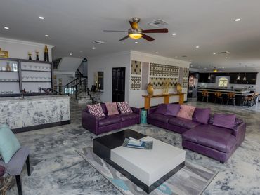 Modern open-concept living room with purple sofas and a sleek kitchen in the background.
