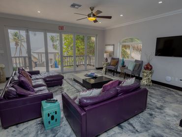 Modern living room with purple leather sofas and ocean view.