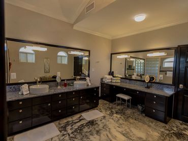 Spacious bathroom with dual sinks, large mirrors, and dark cabinetry.
