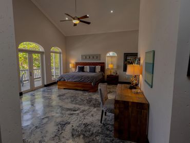 Spacious bedroom with wooden furniture and large windows opening to a balcony.