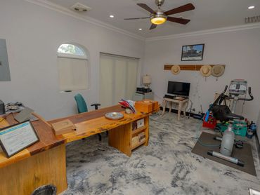 Spacious office with wooden desk, exercise bike, and TV mounted on the wall.