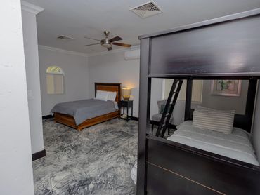 Modern bedroom with a single bed, bunk bed, and gray bedding.