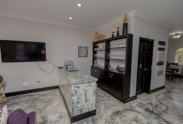 Modern home bar with marble island and dark wood shelving.