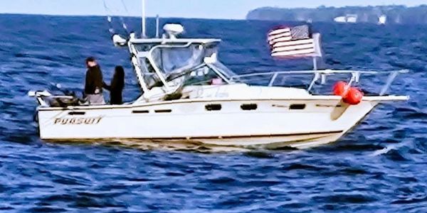 Boat with American flag sailing on a calm sea.