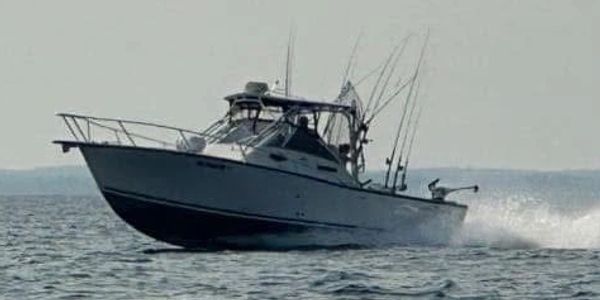 A motorboat speeding across the ocean with fishing rods.