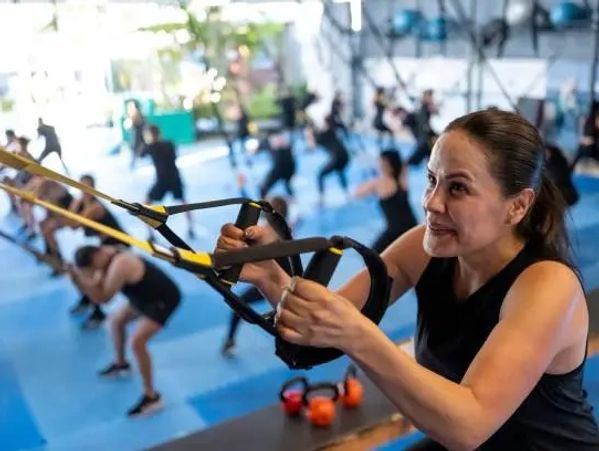 Woman intensely exercising with suspension straps in gym class.