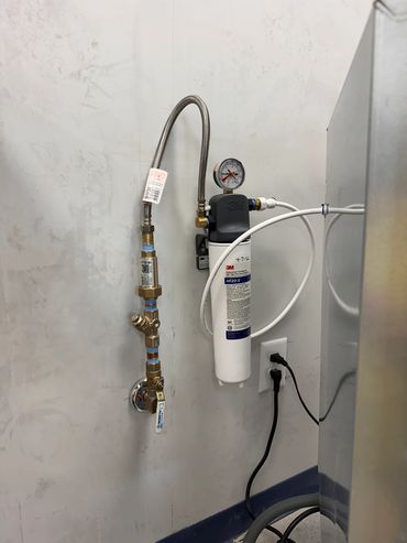 Water filtration system with pressure gauge and flexible hose.