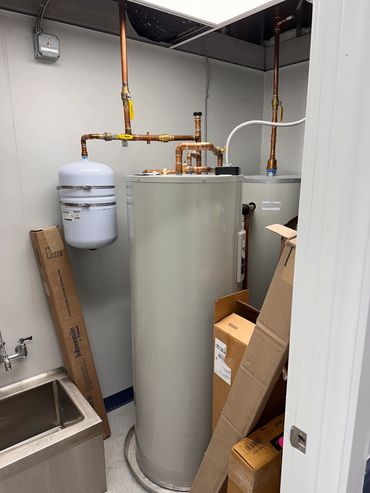 A utility room with water heaters and pipes.