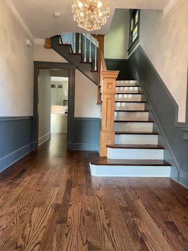 Hardwood floors with antique railing in stairwell. Bold wall paneling and trim.