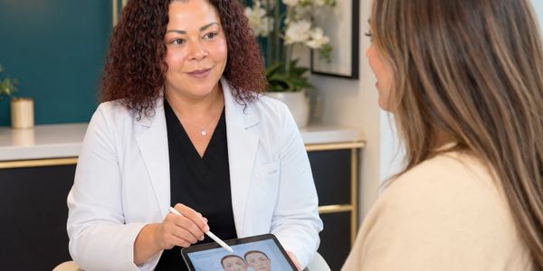 A professional shows a facial analysis on a tablet to a client.