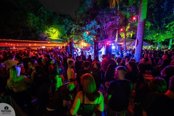 A vibrant outdoor night party with colorful lights and a large crowd.