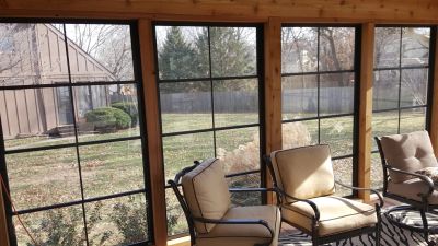 Cozy screened porch with patio chairs and outdoor view.