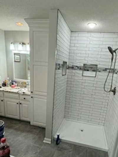 Modern bathroom with a white tiled walk-in shower and vanity area.