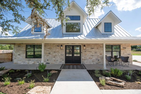 Stone house with a metal roof and black double front doors.