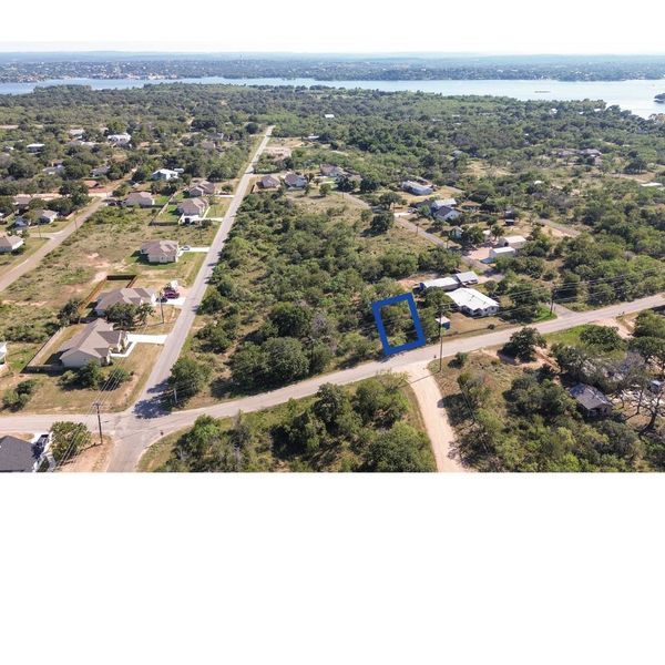 Aerial view of a residential area with scattered houses and a blue-marked plot.