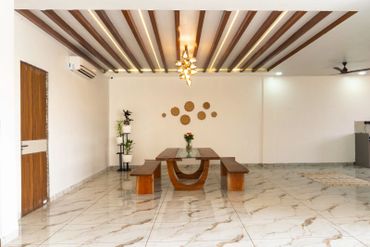 Minimalist dining area with wooden table and benches under modern ceiling lights.