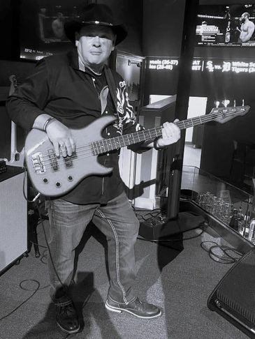 Man playing electric bass guitar in a casual setting.