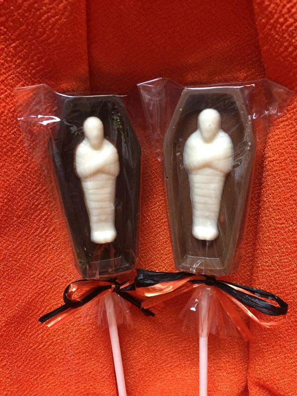 Milk or dark chocolate coffin pop with a white chocolate mummy inside. Tied in halloween colors.