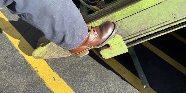 Person stepping down from a green metal platform.