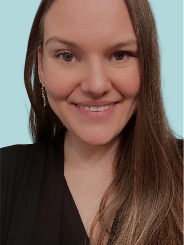 Smiling woman with long brown hair and elegant earrings against a light blue background.