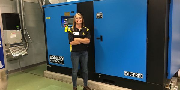 sales person standing in front of a Kobelco oil free rotary screw compressor