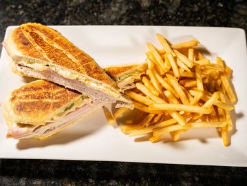Classic Cuban sandwich with roasted pork, ham, Swiss cheese, pickles, and mustard, pressed until cri