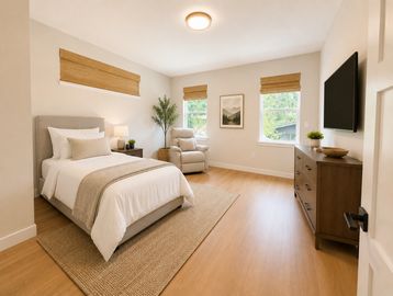 Bright bedroom with a cozy bed, armchair, and wooden dresser.