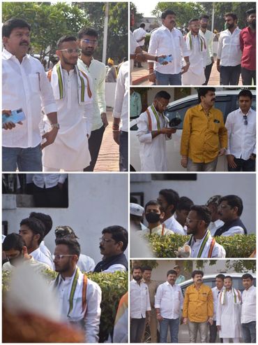 Group of men in traditional and casual wear gathered outdoors, some holding phones and papers.