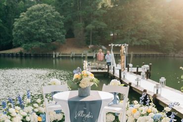 Elegant lakeside wedding setup with floral decorations and a dock.