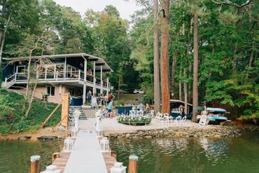 Lakeside gathering with dock, floral decorations, and people enjoying a serene outdoor event.