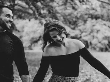 A happy couple walking outdoors, holding hands and smiling.