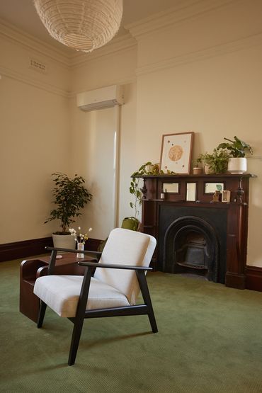 Cozy modern chair near a vintage fireplace with plants and artwork.