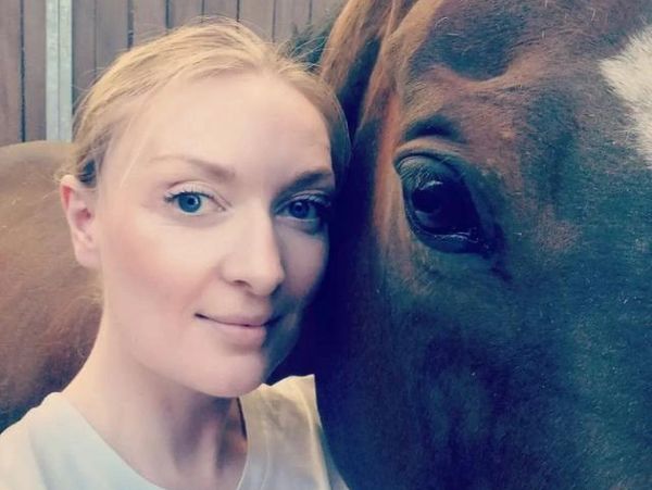 Woman taking a close selfie with a horse.