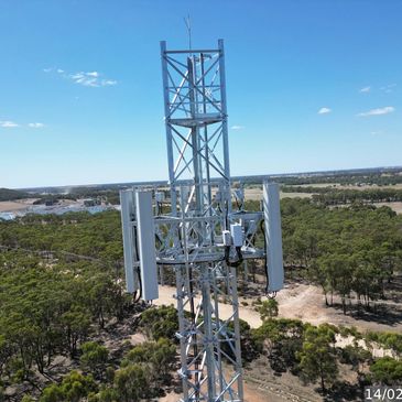 Telecommunication tower standing tall in a rural area under a clear blue sky.