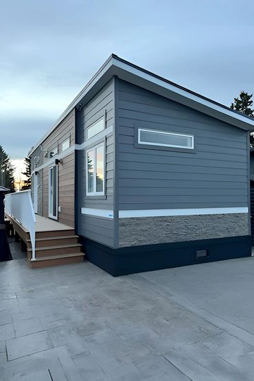 Modern tiny house with gray siding and stone accents at dusk.
