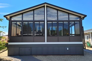 Modern sunroom with large glass windows and a peaked roof.