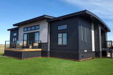 Modern single-story house with mixed dark and light exterior, large windows, and a wooden deck.