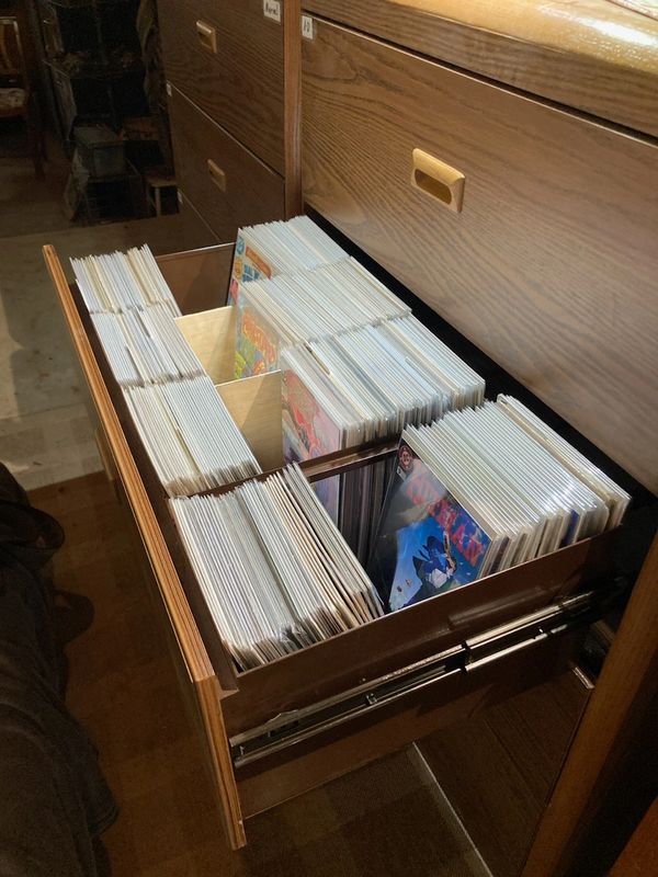 Open drawer filled with organized comic books in plastic sleeves.