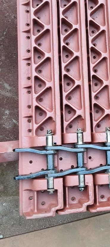 Stacked metal and iron parts with bolts on a workshop floor.