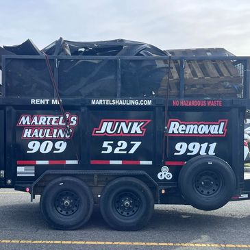 A junk removal trailer from Martel's Hauling filled with renovation debris, parked in a lot.