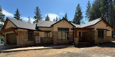 Modern single-story house with stone and beige exterior under clear blue sky.