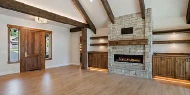 Spacious living room with wooden beams, stone fireplace, and built-in shelves.