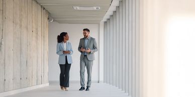 Two professionals walking and talking in a modern office corridor.