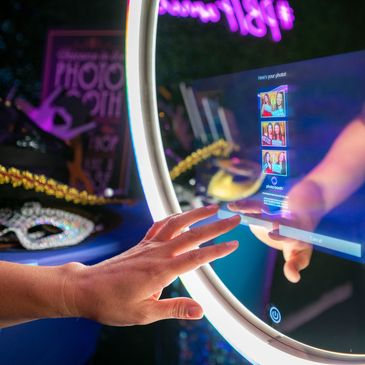 A hand reaching out to touch the mirror photo booth touchscreen