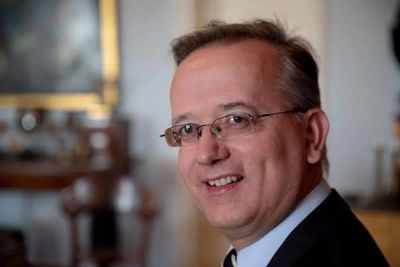 Porträt eines lächelnden Mannes mit Brille.